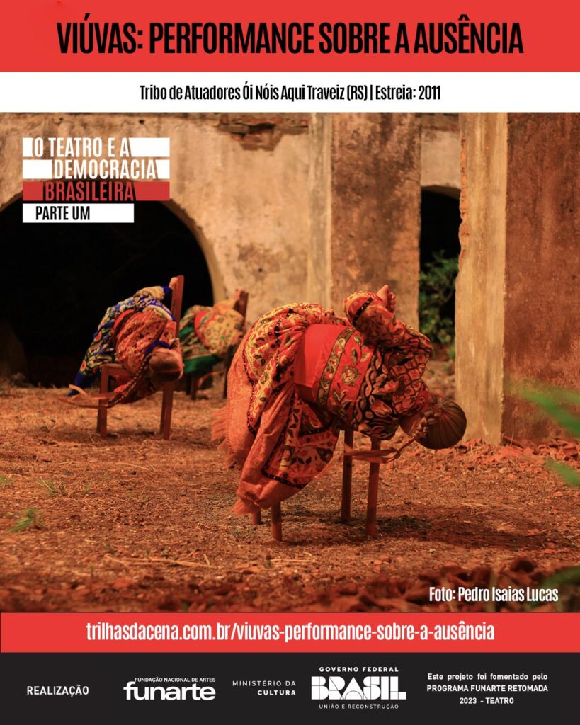 Três mulheres com roupas coloridas se inclinam com seus corpos sobre cadeiras. A cena externa na grama seca e algumas plantas é emoldurada por ruínas. Texto promove Viúvas: Performance Sobre a Ausência da Tribo de Atuadores Ói Nóis Aqui Traveiz.