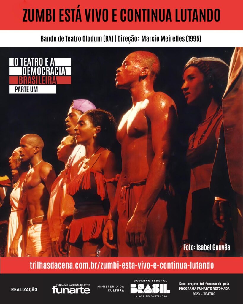 Arte de divulgação. Um grupo de artistas fica lado a lado no palco, voltado para a frente. Eles usam trajes e acessórios de cabeça coloridos e minimalistas, com uma iluminação dramática que destaca suas expressões e corpos. Foto: Isabel Gouveia